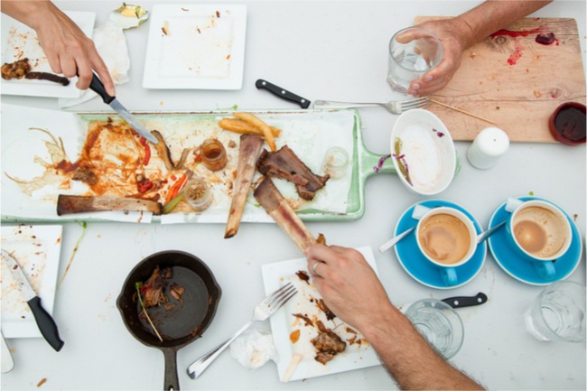 Finished leftover dinner party table empty of food and messy dishes on a carpet