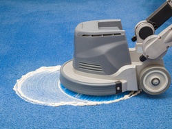 Professional disk machine cleaning on a blue carpet. Chemical foaming, rubbing and cleaning on carpet.