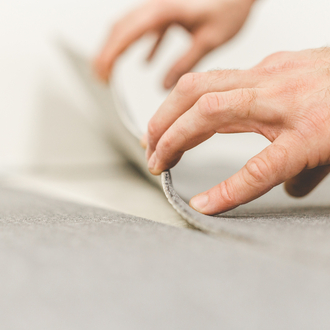 A close-up of a person installing Flotex carpeting is shown.