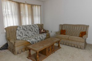 A living room with vintage upholstered furniture and a coffee table.