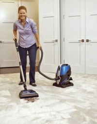 A young woman vacuums the living room floor. Concept, water-based vacuum cleaners.