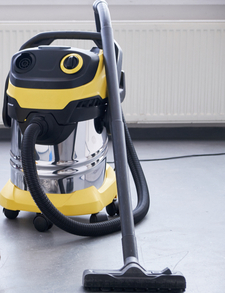 A yellow water vacuum cleaner in the middle of a clean tiled floor.