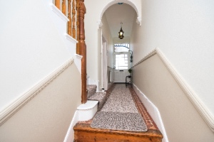 The entrance hallway features a carpet runner and wooden banister, illustrating hallway runner rules.